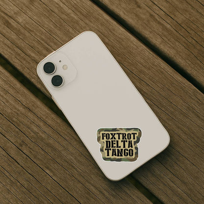 White phone with a 'Foxtrot Delta Tango' sticker on a wooden surface