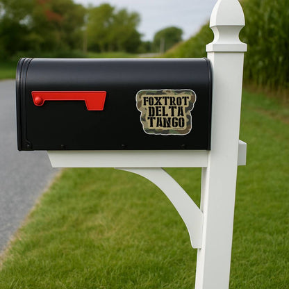 Black mailbox with 'Foxtrot Delta Tango' label on a white post in a grassy area.