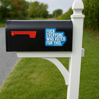 Black mailbox with a blue and white sticker on a grassy lawn