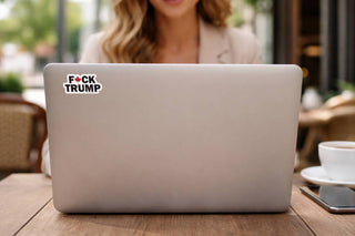 Laptop with a sticker on a wooden table in an outdoor setting