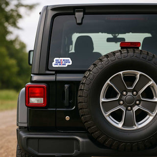 A close-up rear view of a black off-road vehicle with a spare tire mounted on the back door. A small rectangular sticker is visible on the rear window, reading 'GUA DE MEXICO TERRITORY OF COLORADO JANE 07 2026'.