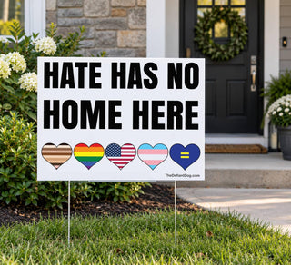 18x24 Hate Has No Home Here white corrugated plastic yard sign displayed on a metal stake in a front lawn near a house entrance.
