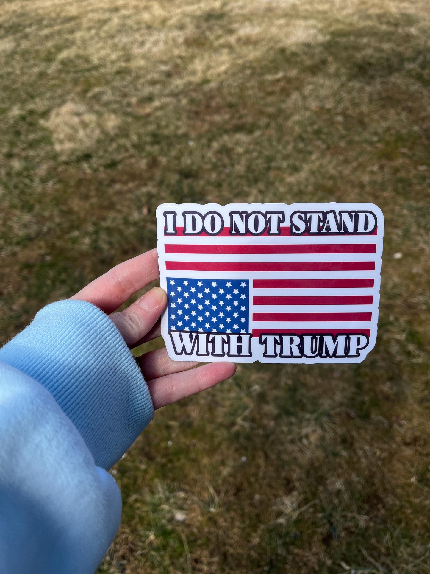 'I Do Not Stand with Trump' magnet or vinyl decal displayed in hand. A bold, high-quality political sticker perfect for cars, laptops, fridges, or toolboxes. Great for activists, protestors, or anyone fed up with fascism.