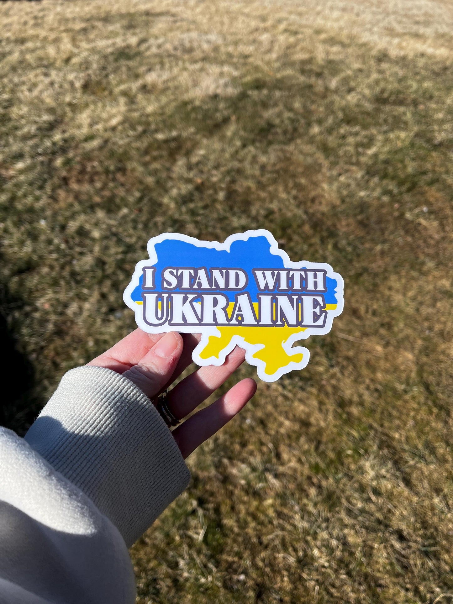 'I Stand with Ukraine  Slava Ukraini' magnet or vinyl decal displayed in hand. A bold, high-quality political sticker perfect for cars, laptops, fridges, or toolboxes. Great for activists, protestors, or anyone fed up with fascism.