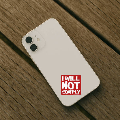 Phone case with 'I WILL NOT COMPLY' text on a wooden surface
