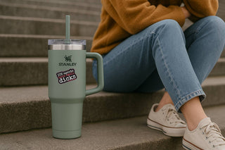 Person sitting on steps with a Stanley tumbler in the foreground