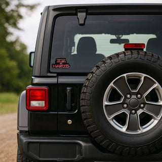 Black Jeep Wrangler with spare tire and visible 'Ice = Nazis' decal on a blurred natural background