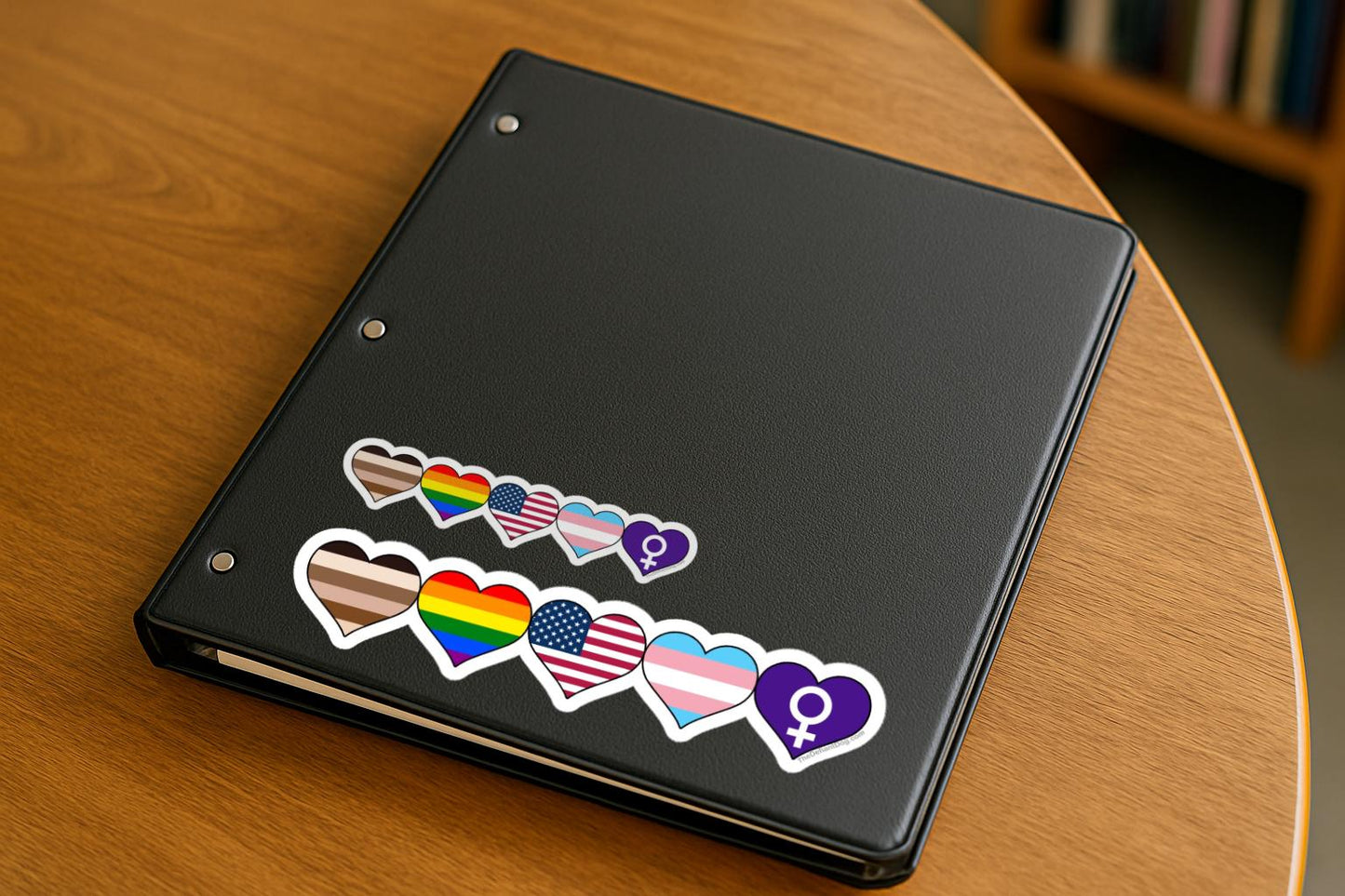 Black tablet with pride-themed stickers on a wooden surface