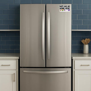 Stainless steel refrigerator with a 'Hate Has No Home Here' magnet on a blue tiled wall.