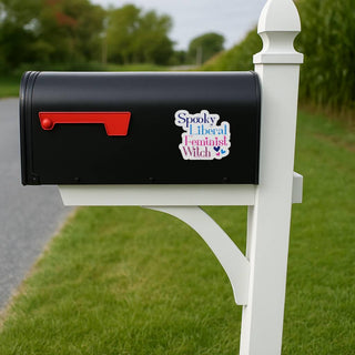 Black mailbox with a colorful sticker on a white post in a grassy area.