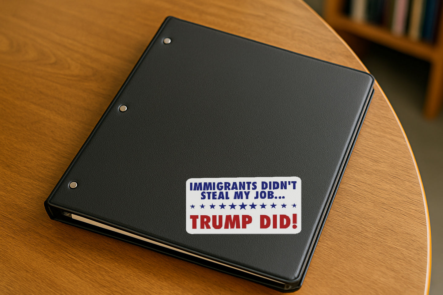 Immigrants Didn't Steal My Job  Trump Did' magnet or vinyl decal displayed on a black binder in a library. A bold, high-quality political sticker perfect for cars, laptops, fridges, or toolboxes. Great for activists, protestors, or anyone fed up with fascism.