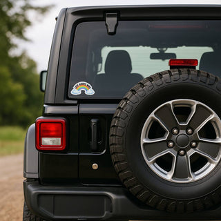 Love Always Wins rainbow sticker displayed on the rear window of a black Jeep. The colorful pride design contrasts against the tinted glass, showing scale and visibility on vehicle windows.