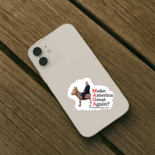 A white smartphone lying on a weathered wooden surface, with a printed sticker on the back showing a donkey carrying an American flag and the text 'Make America Great Again?' plus a website URL.