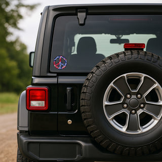 Close-up rear view of a black off-road vehicle with a spare tire mounted on the back, featuring a circular peace sign decal with a red, white, and blue design on the rear left side.