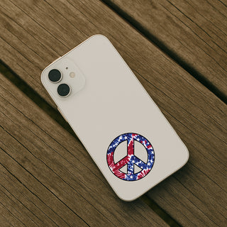 A white smartphone case shown from the back, placed on a rustic wooden surface. The case features a circular peace sign graphic filled with an American flag pattern of red, white, and blue stars and stripes.