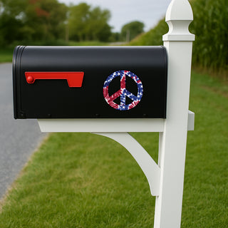 A black mailbox mounted on a white post outdoors, with a red flag and a peace sign decal featuring a red, white, and blue American flag pattern.