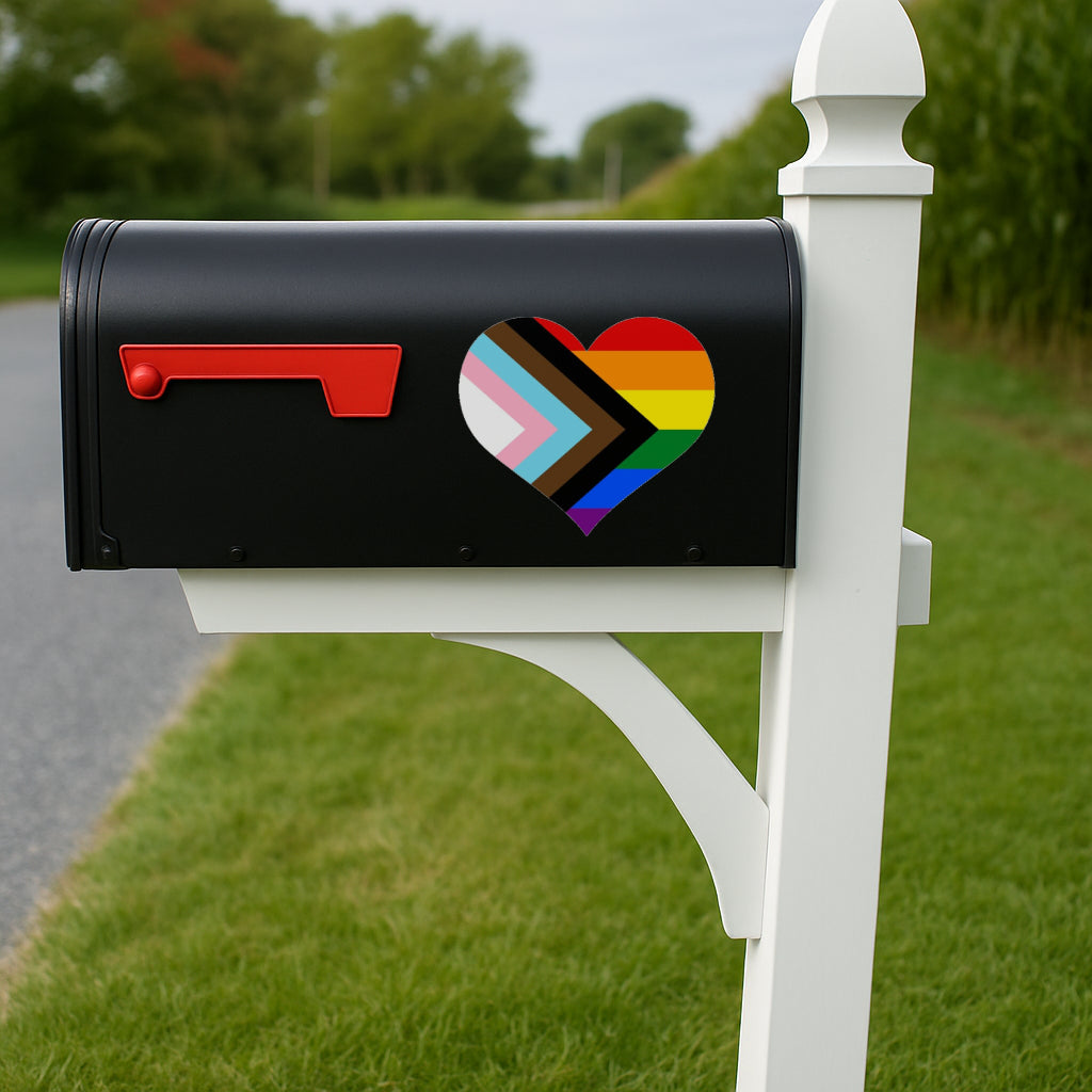 Black mailbox with a rainbow heart design on a white post in a grassy area.
