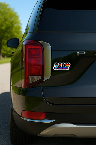 Progress pride “ALLY” sticker on the rear of a black vehicle