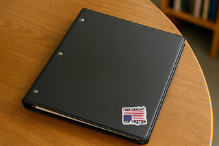 Rage Against the Regime distressed American flag protest sticker on the back of a silver laptop at an outdoor café table.