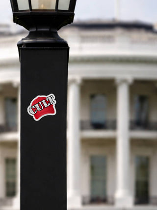 Black lamp post with 'CULT' sticker in front of a blurred building