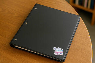 Black notebook with a sticker on a wooden surface