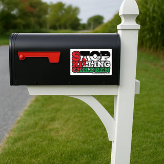 A black mailbox mounted on a white post outdoors, with a red flag and a rectangular sticker that reads “STOP KILLING CHILDREN” in red, black, and green lettering.