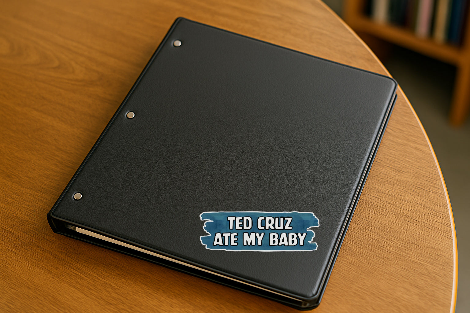 Ted Cruz Ate My Baby' magnet or vinyl decal displayed on a black binder in a library. A bold, high-quality political sticker perfect for cars, laptops, fridges, or toolboxes. Great for activists, protestors, or anyone fed up with fascism.