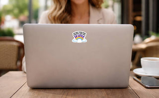 Love is stronger than hate vinyl decal centered on the back of a laptop at an outdoor cafe