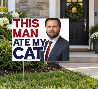 This Man Ate My Cat funny anti-MAGA political lawn sign with bold patriotic lettering and JD Vance's portrait, displayed in a landscaped front yard outside a suburban home.