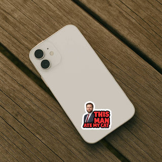 Phone case with 'This Man Ate My Cat' sticker on a wooden surface