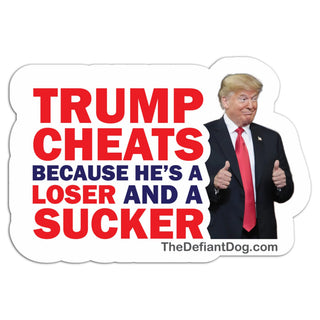 A die-cut sticker featuring a photo of Donald Trump giving a thumbs-up alongside bold political text reading 'TRUMP CHEATS BECAUSE HE'S A LOSER AND A SUCKER' in red and navy on a white background, with 'TheDefiantDog.com' printed below.