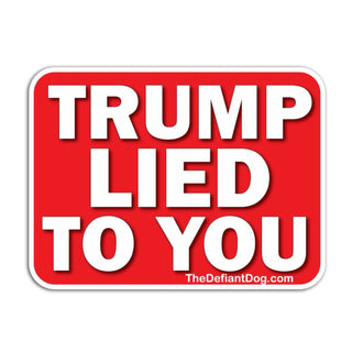 A rectangular red sign with rounded corners and bold white text reading 'TRUMP LIED TO YOU'. Small website text 'TheDefiantDog.