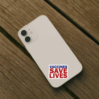 Phone with 'Vaccines Save Lives' sticker on a wooden surface