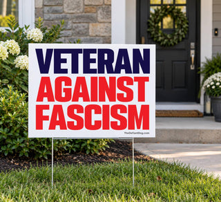 Veteran Against Fascism lawn sign displayed on a metal stake in a front yard near a home entrance.