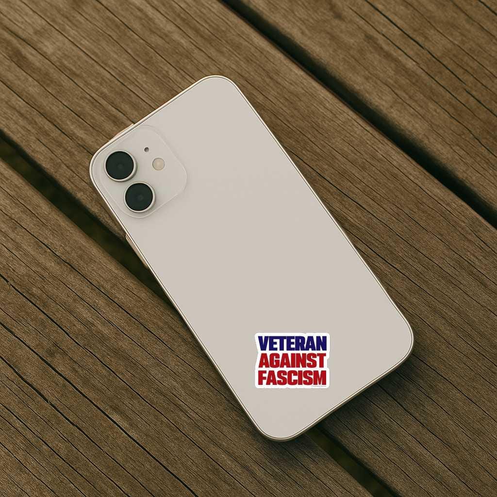 White smartphone with 'Veteran Against Fascism' sticker on a wooden surface