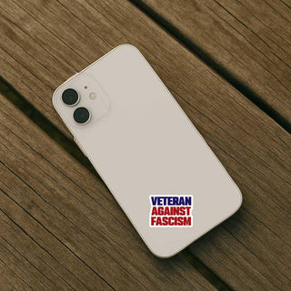 White smartphone with 'Veteran Against Fascism' sticker on a wooden surface