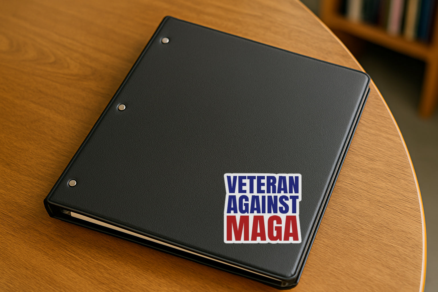 Veteran Against MAGA' magnet or vinyl decal displayed on a black binder in a library. A bold, high-quality political sticker perfect for cars, laptops, fridges, or toolboxes. Great for activists, protestors, or anyone fed up with fascism.