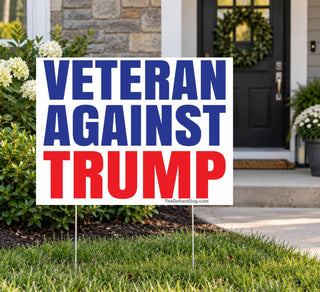 Veterans Against Trump political protest yard sign positioned outside a suburban home with green grass and flowering shrubs, featuring bold patriotic red, white, and blue typography.