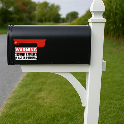 'Warning Security Cameras in Use' magnet or vinyl decal displayed with a slight shadow on black mailbox
