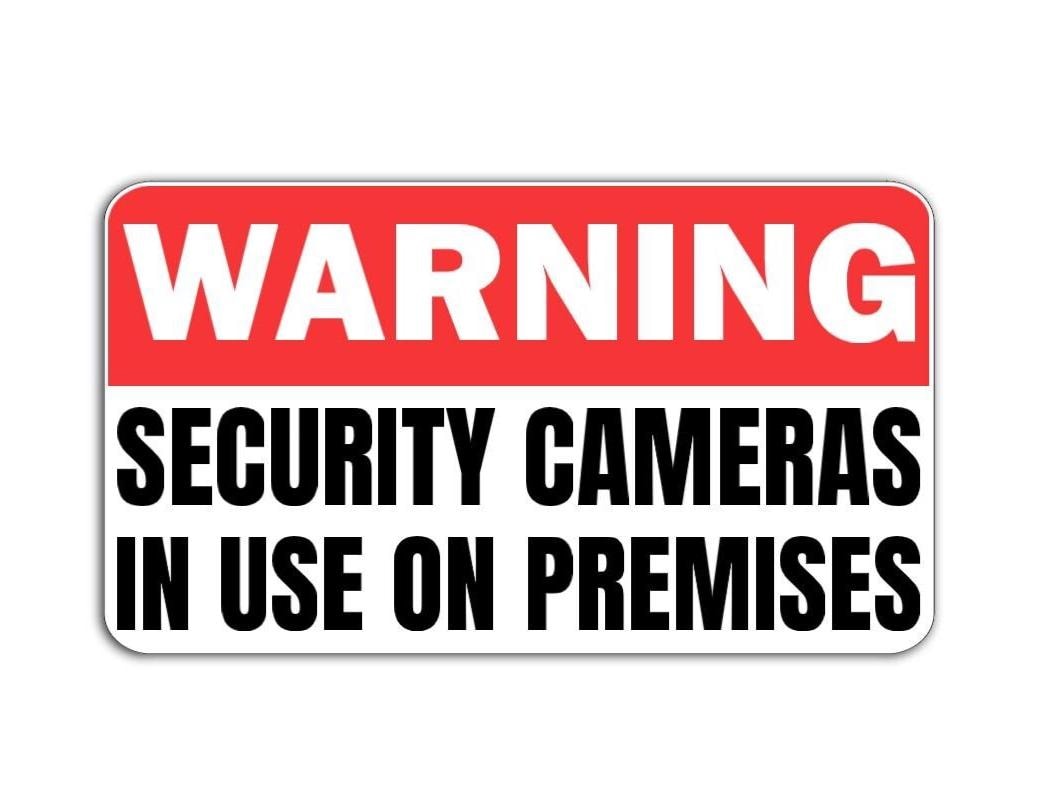 'Warning Security Cameras in Use' magnet or vinyl decal displayed with a slight shadow on a white background. 
