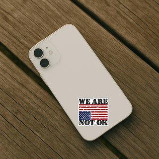 Phone case with 'We Are Not OK' design on a wooden surface