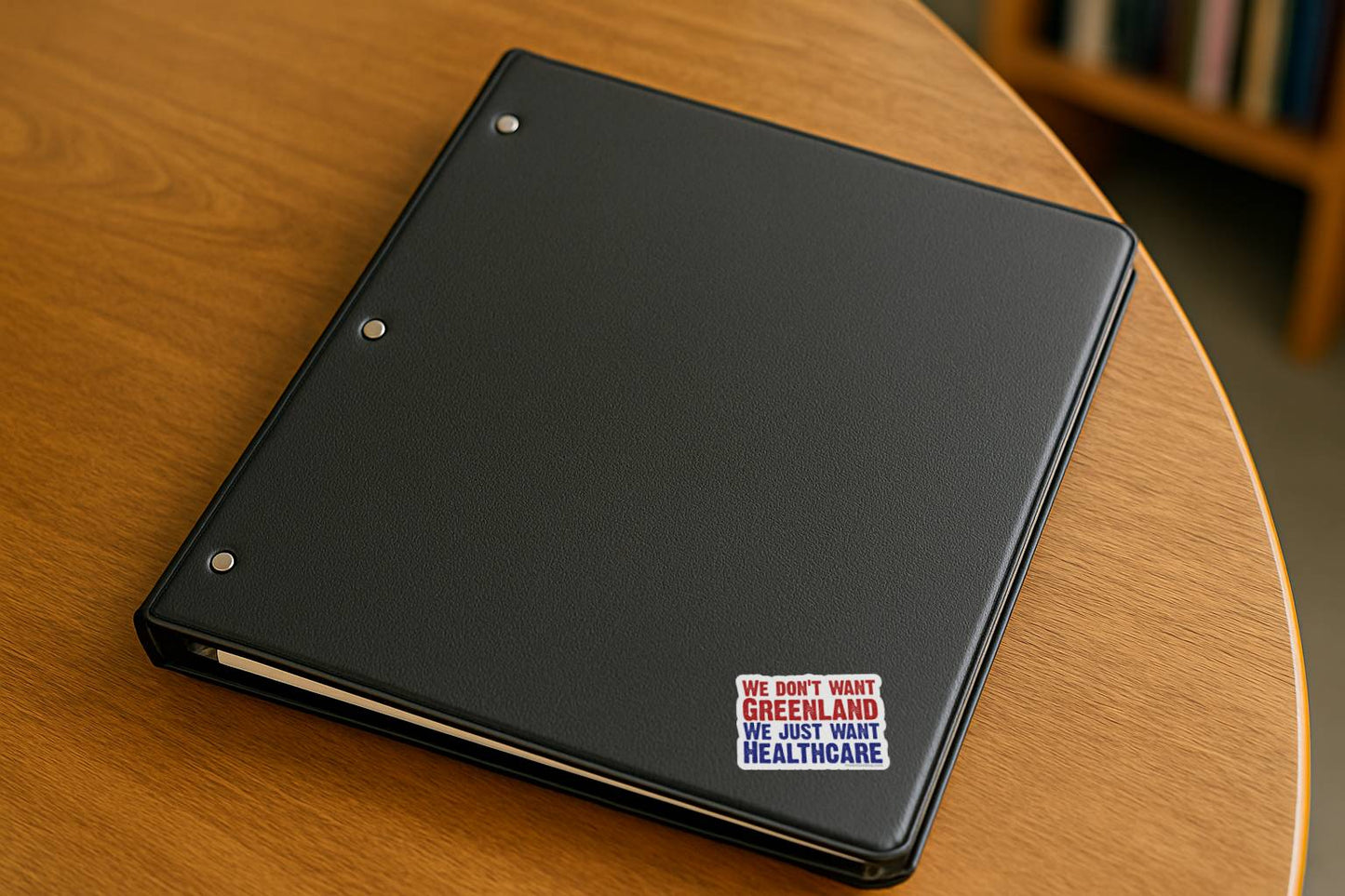 Black notebook with a sticker on a wooden surface