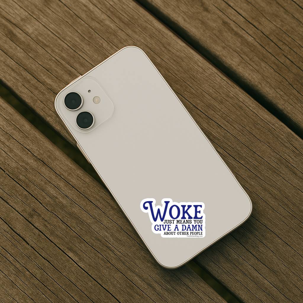 Light colored iPhone placed on wooden surface with Woke Just Means You Give a Damn About Other People vinyl sticker applied to the back. Compact political statement decal perfect for phones and cases.