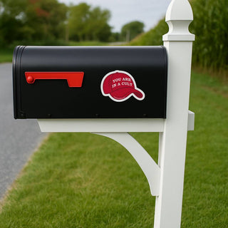 Black mailbox with a red and white sticker on a white post in a grassy area.