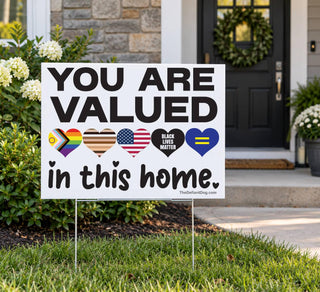 You Are Valued in This Home inclusive yard sign displayed on a metal H-stake in a front lawn beside a home's entrance.