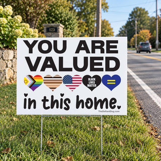 You Are Valued in This Home lawn sign displayed beside a neighborhood road with Pride, diversity, Black Lives Matter, and equality hearts.