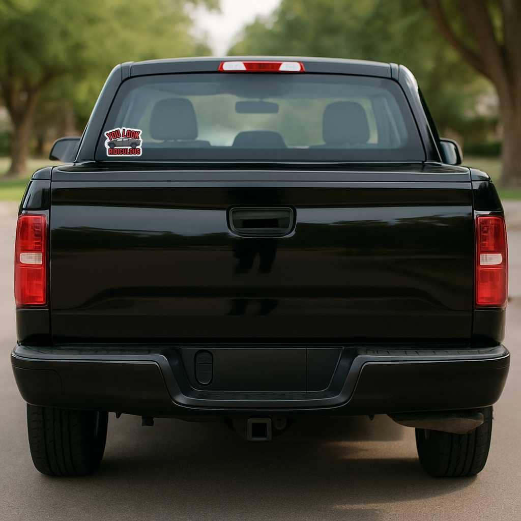 Black pickup truck with a visible license plate on a road with trees in the background