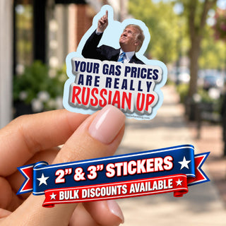 Your Gas Prices Are Really Russian Up Trump political sticker held between manicured fingers, with red, white and blue promotional ribbons advertising 2-inch and 3-inch stickers and bulk discounts.